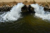 Water gushes from a pipe into a farm irrigation canal in Central California.