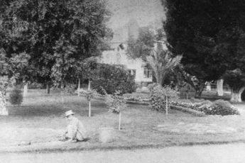 Black and white image of worker in a yard.