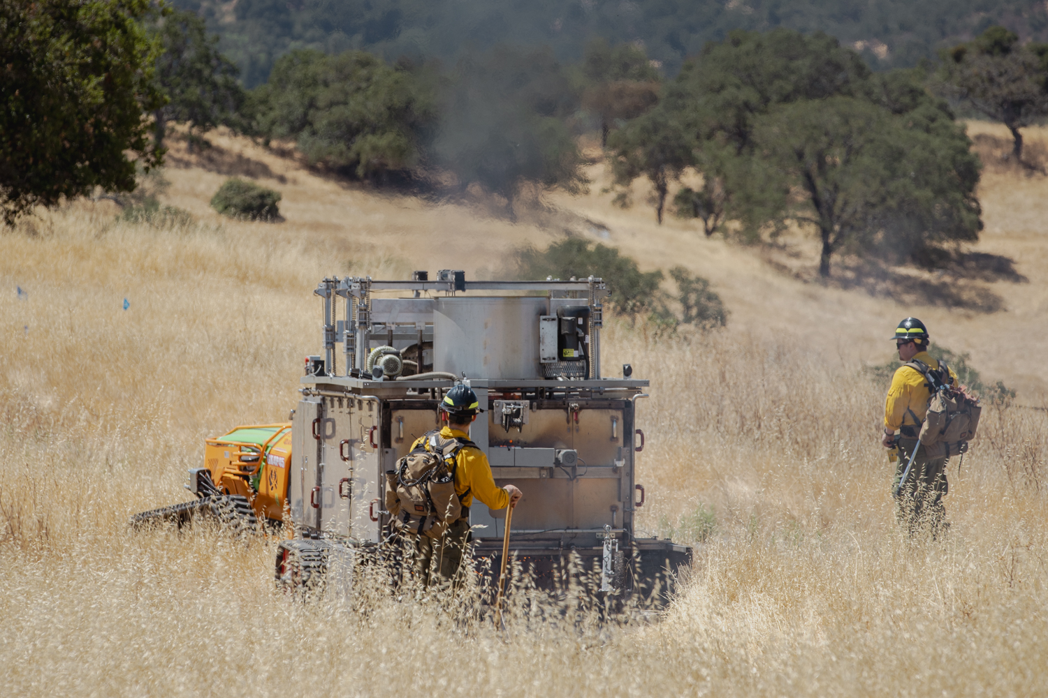 A worker operates BurnBot in a golden field.