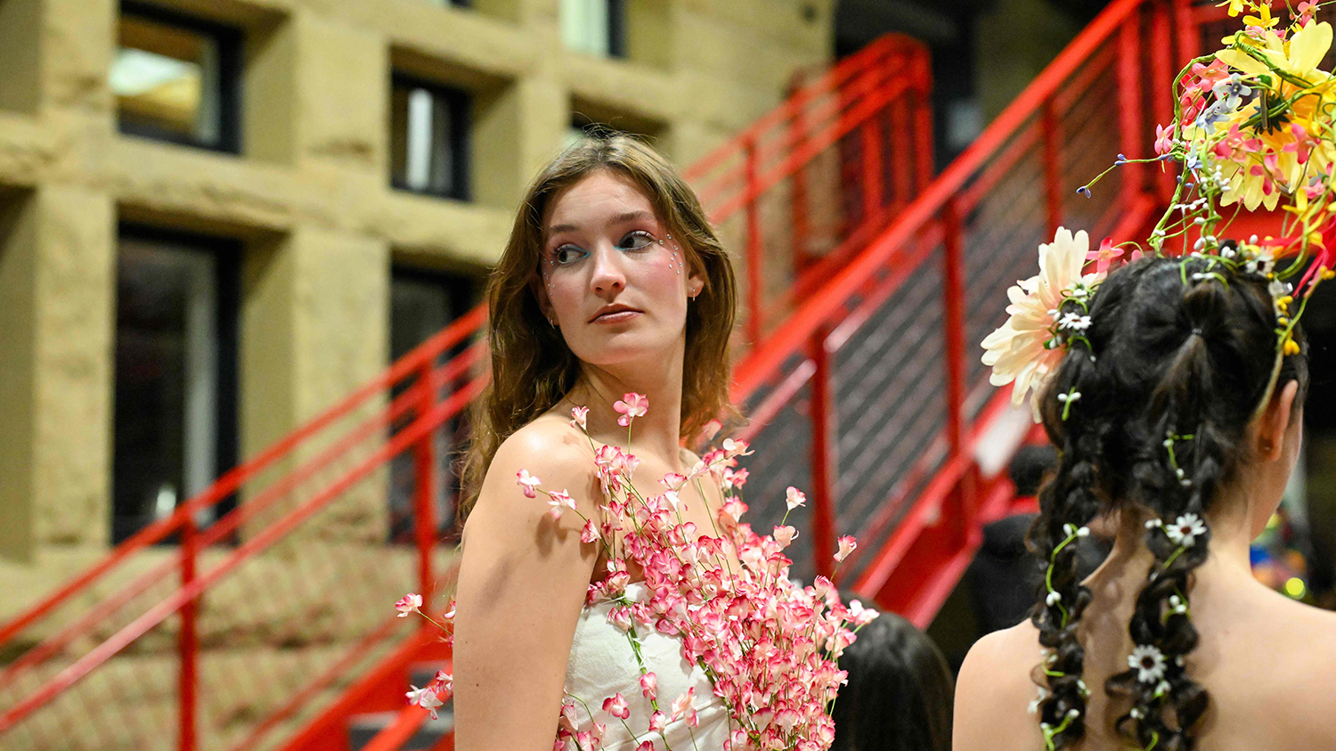 A student model backstage in a flower covered dress.