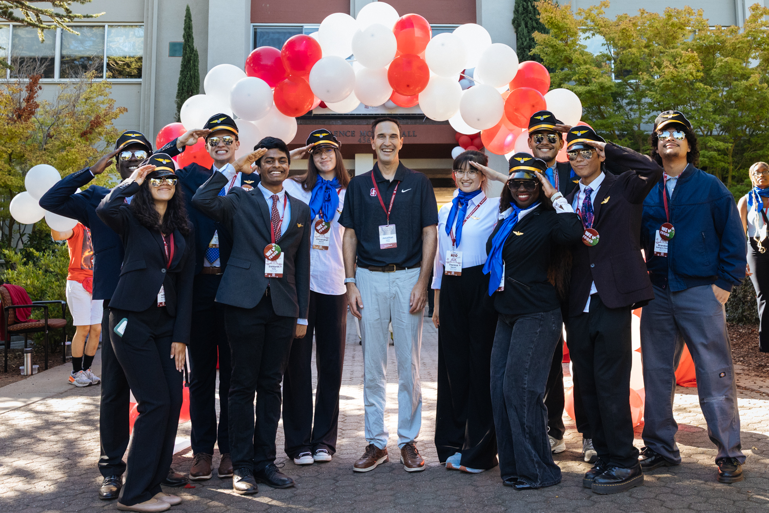 Orientation coordinators pose with the president under a balloon arch outside Florence Moore Hall.