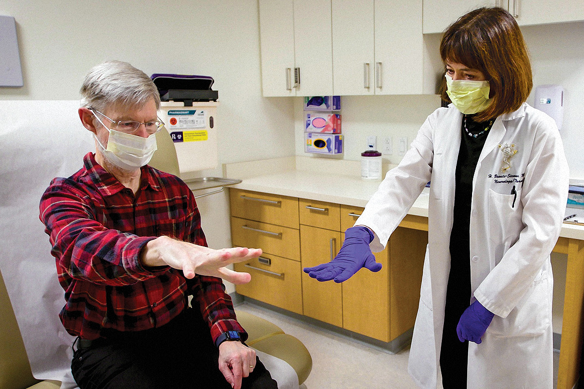 Keith Krehbiel extends his arm during a physical exam with Dr. Helen Bronte-Stewart.
