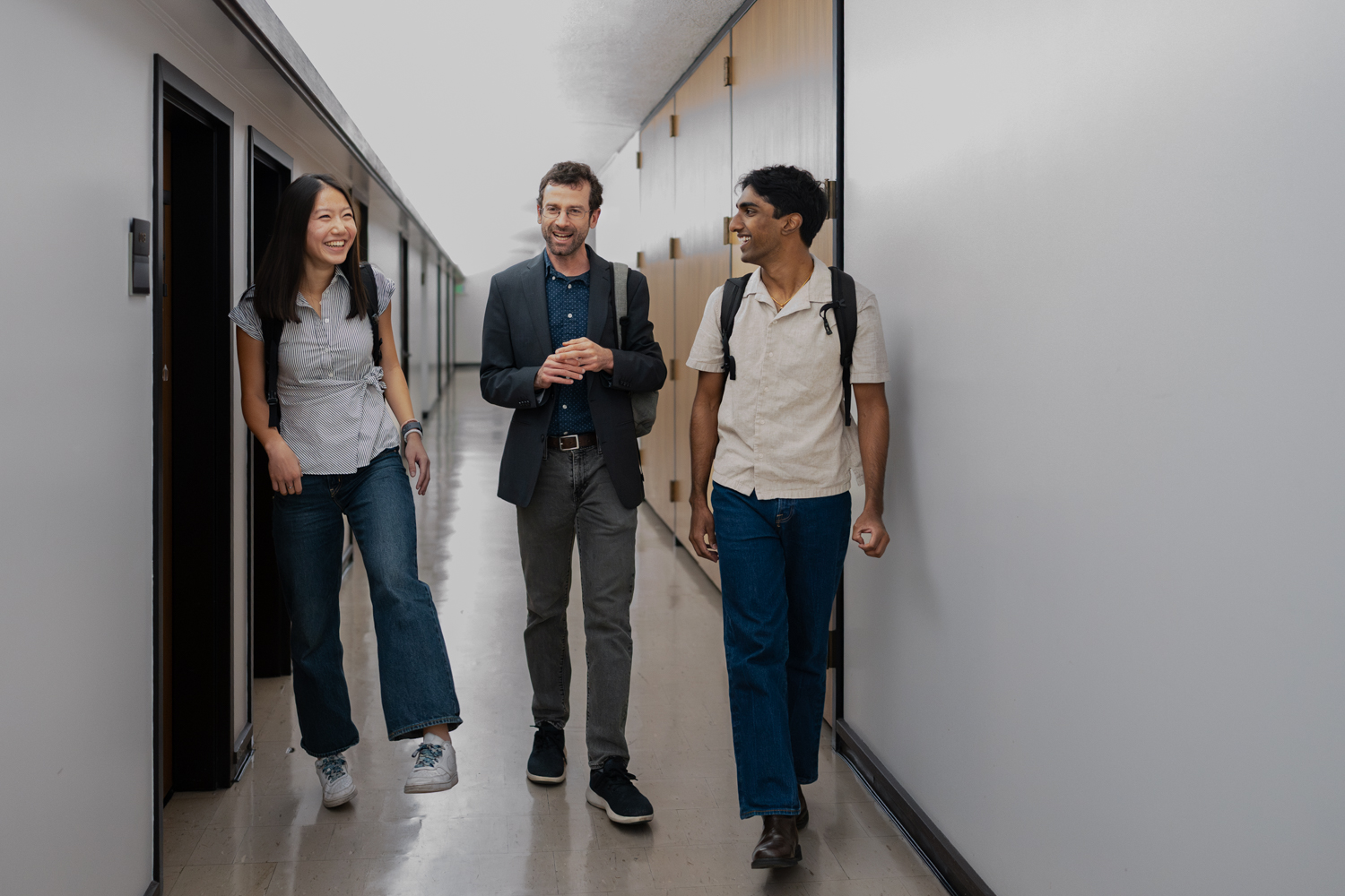 Mary Zheng, Brian Coyne, and Arjun Ayyappan walking together down a corridor.