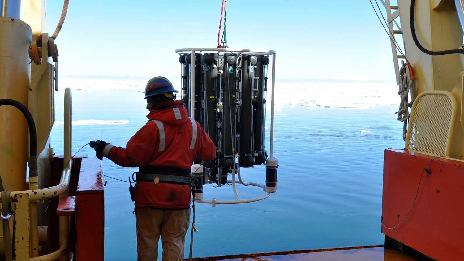 Image of a person on a ship deploying the instrument used to collect water samples from different ocean depths.