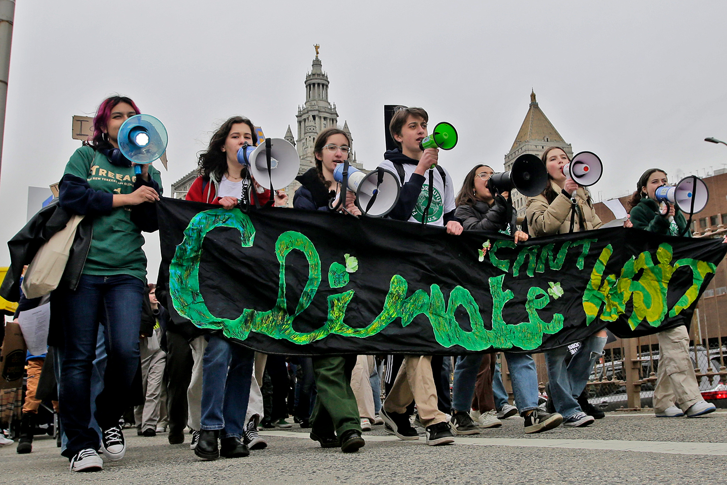 Young adults walk across the Brooklyn Bridge during a demonstration for climate.