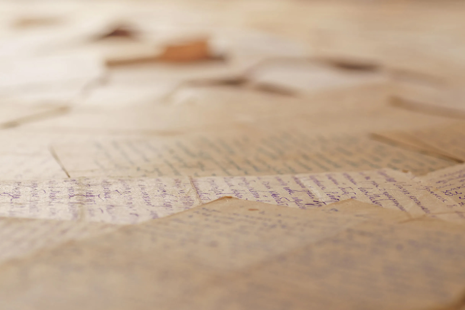 Table covered with many old letters. Angle view, selective focus. Text is unrecognizable.