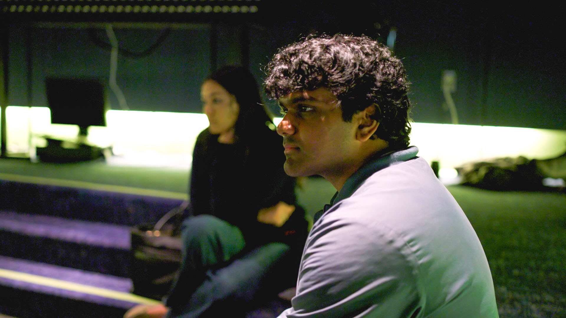 Two students are seated in a dimly lit recording studio.