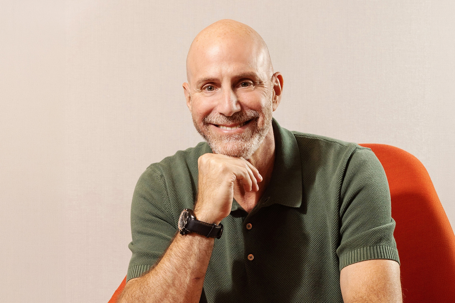 Smiling Josh Silverman with a bald head and beard sits thoughtfully in a green polo shirt against a neutral background.