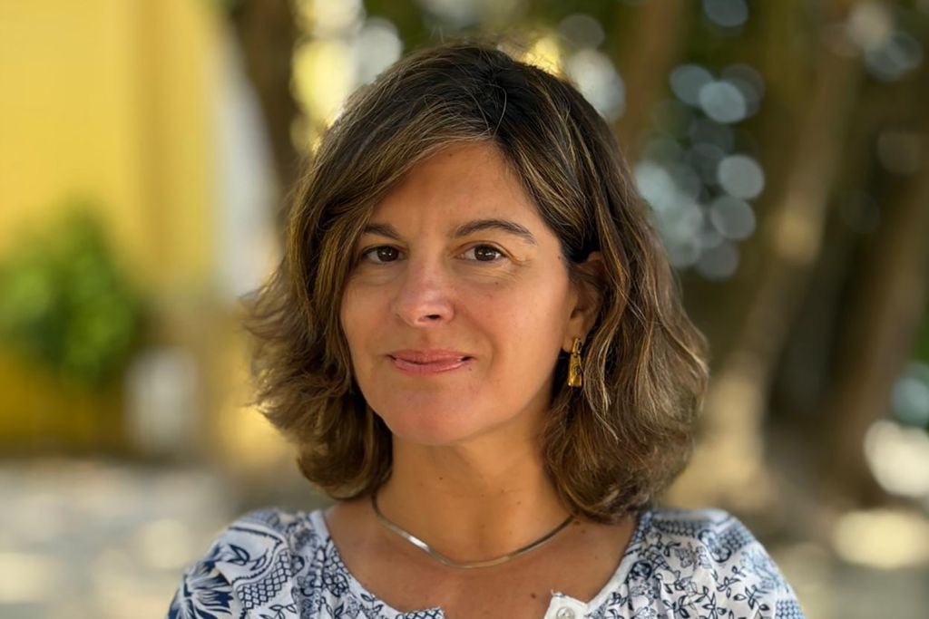 Inês Azevedo posing for a profile photo outdoors against a blurred background.