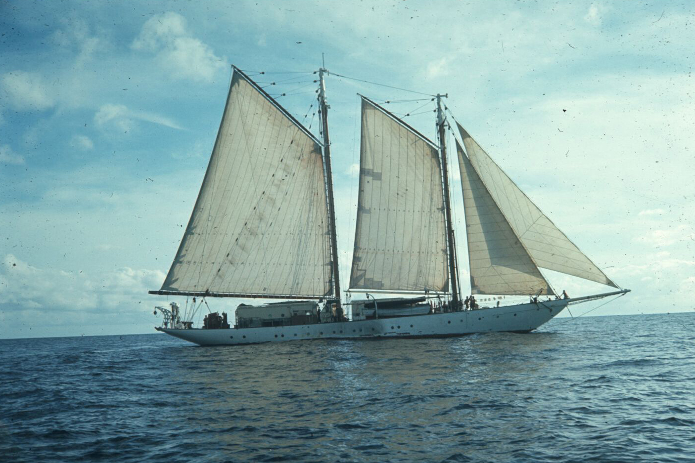 Two-masted schooner under full sail on open ocean.