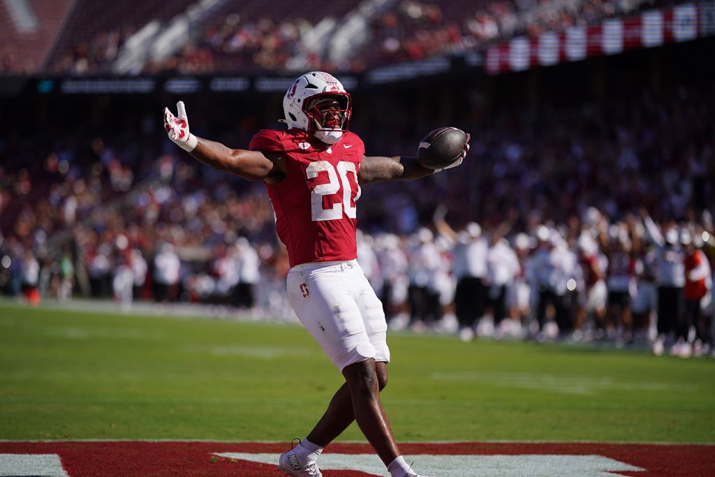 Micah Ford raises his arms in celebration in the end zone after scoring a touchdown during a football game.