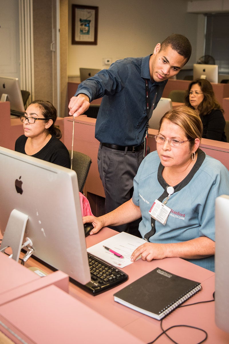 Stepping Stones to Success teacher Frank Larteri assists Stanford Health Care employees in a computer class.