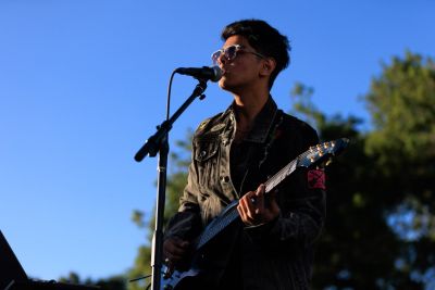 Student playing a guitar on stage.