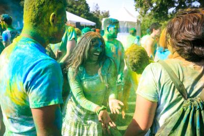 Students covered in colored dust, smiling.