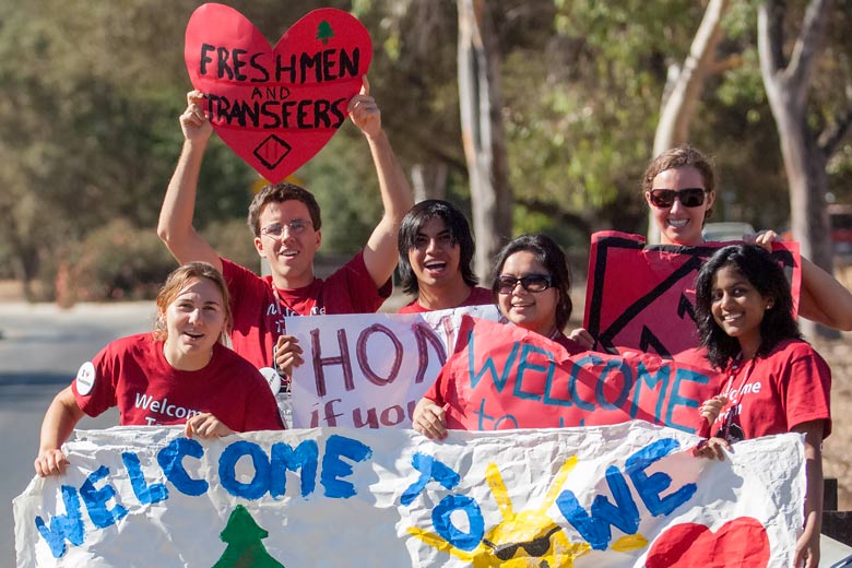 Orientation volunteers hold signs to welcome new students to campus