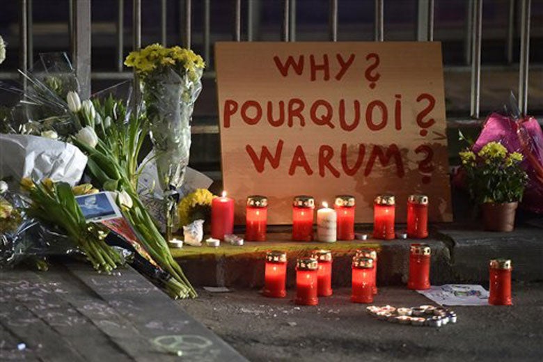 Sign reads 'Why?' in multiple languages at a memorial near Maelbeek metro station in Brussels