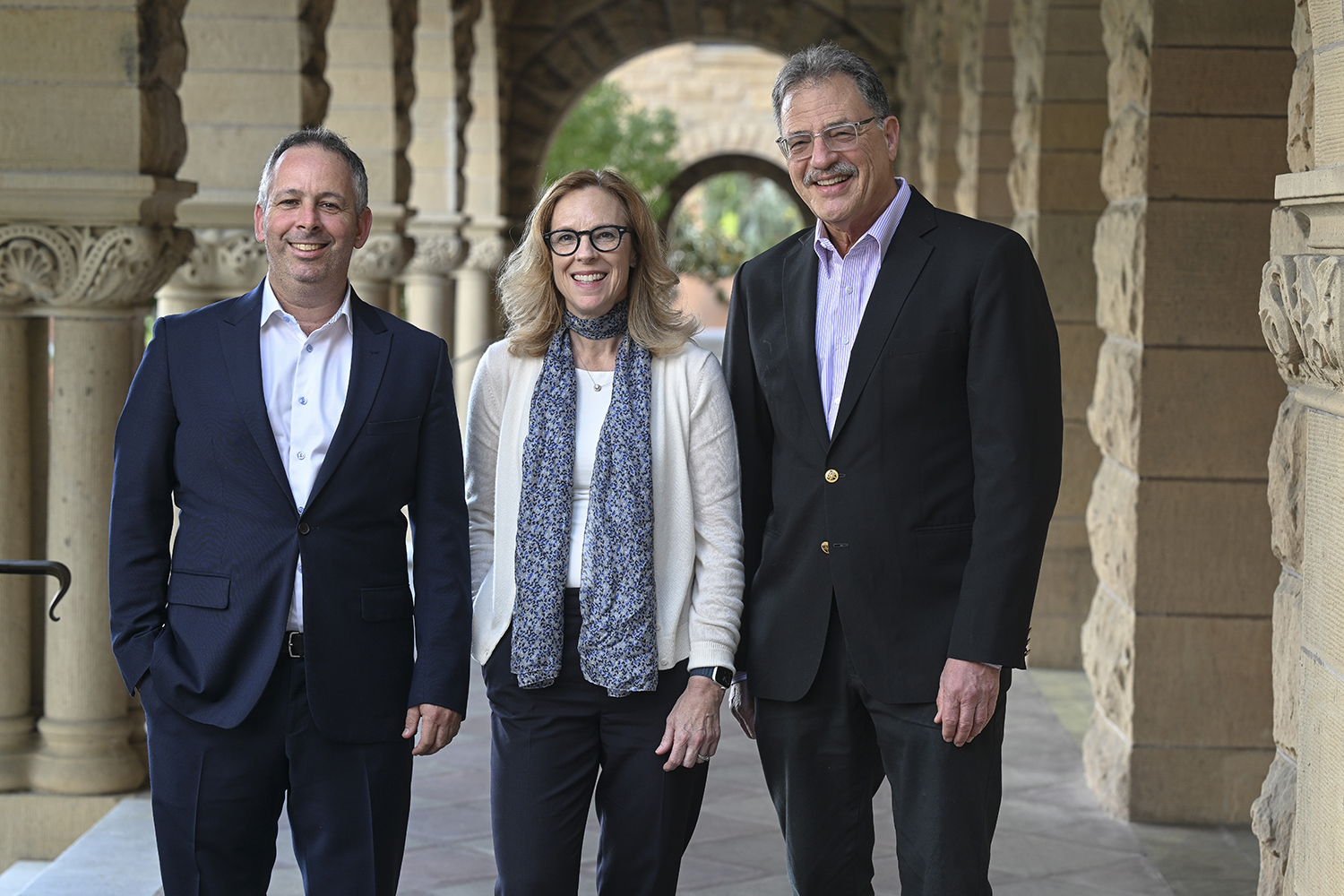 Amichai Magan, Kathryn Stoner, and Larry Diamond standing in sandstone arcade.