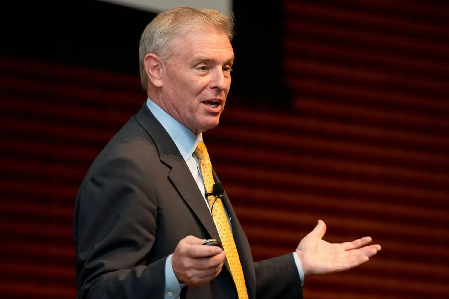 Joel Peterson speaking and gesturing to an audience at Stanford.