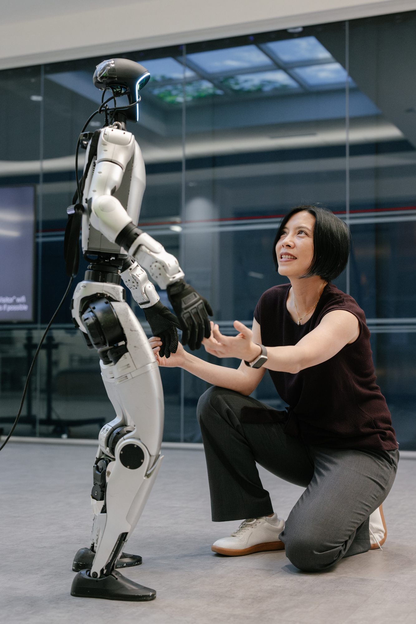 Karen Liu holding hands with a humanoid robot designed in her lab