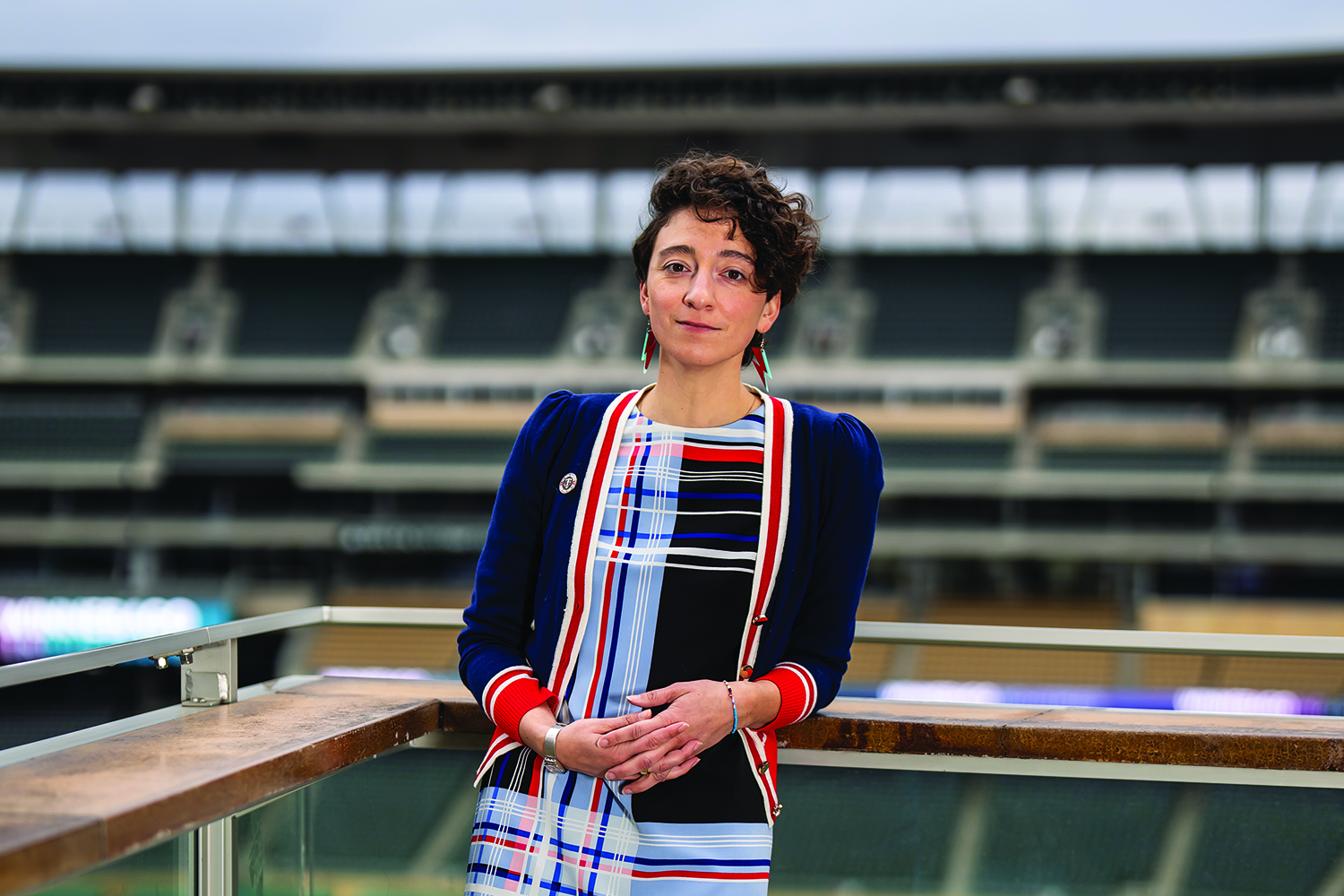 Mari Guttman stands against a stadium backdrop with her hands folded.