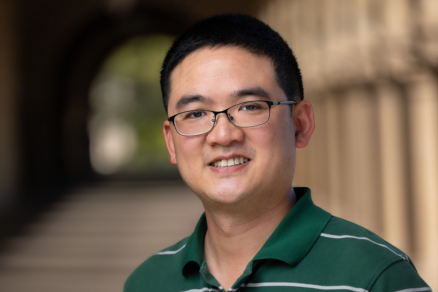 Jonathan Luk wearing glasses and a green striped polo shirt smiling at the camera.