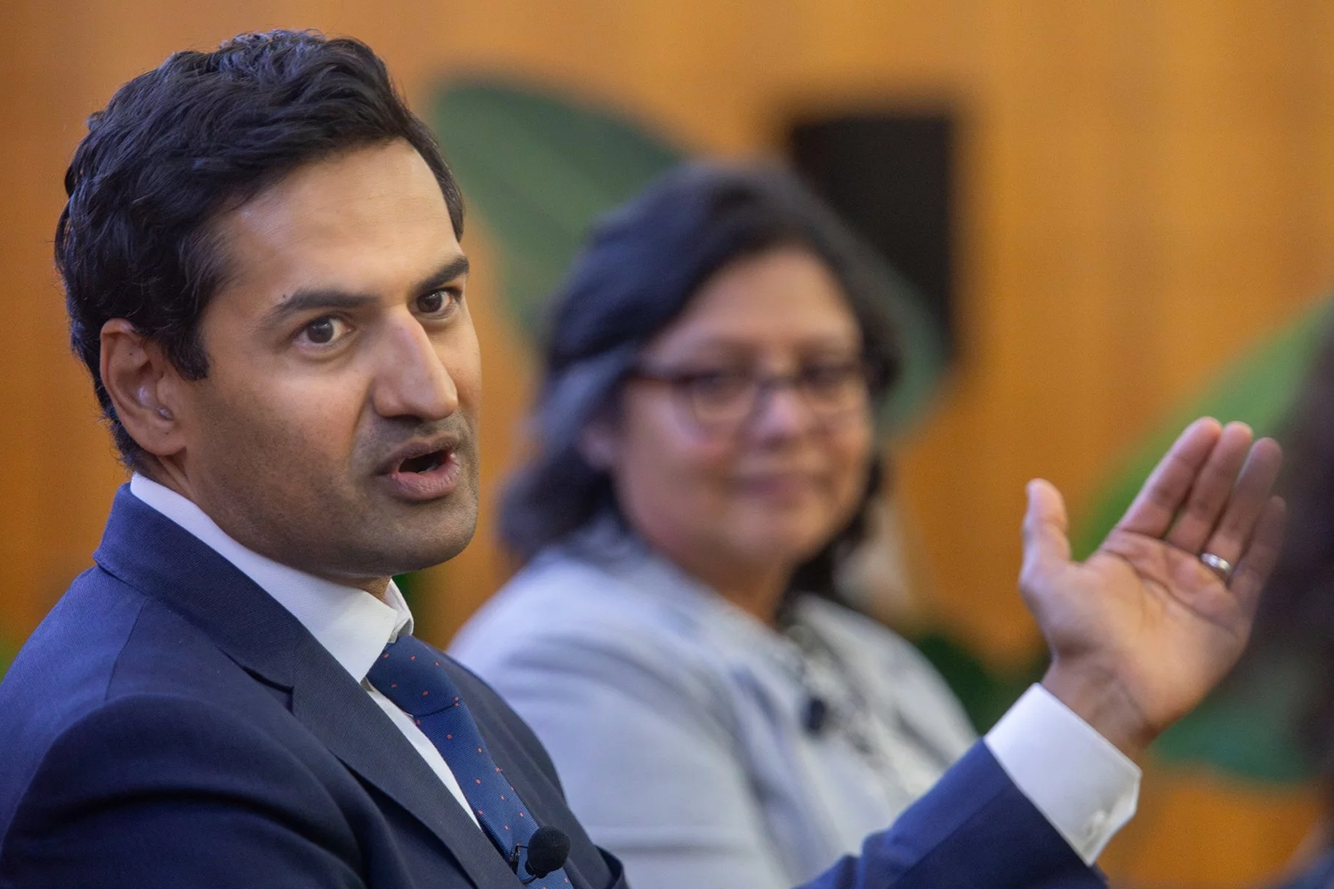 Kunal Modi in a blue suit gestures while speaking during a panel discussion.