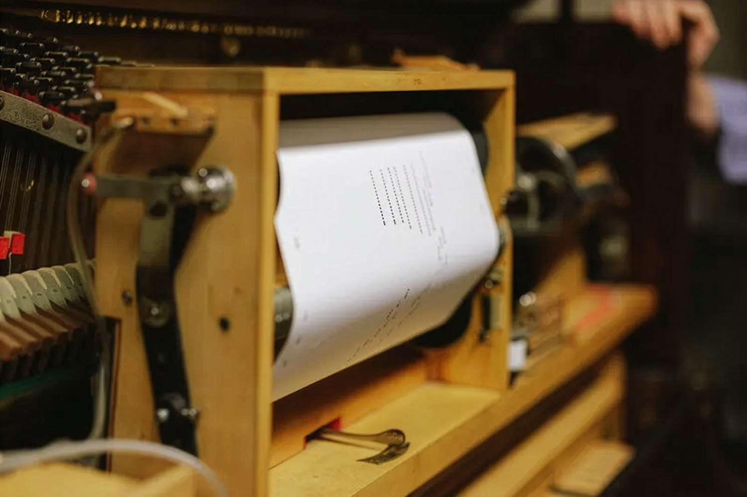 A piano roll with rows of punched holes sits in a player piano's mechanism, encoding music the piano can play back.
