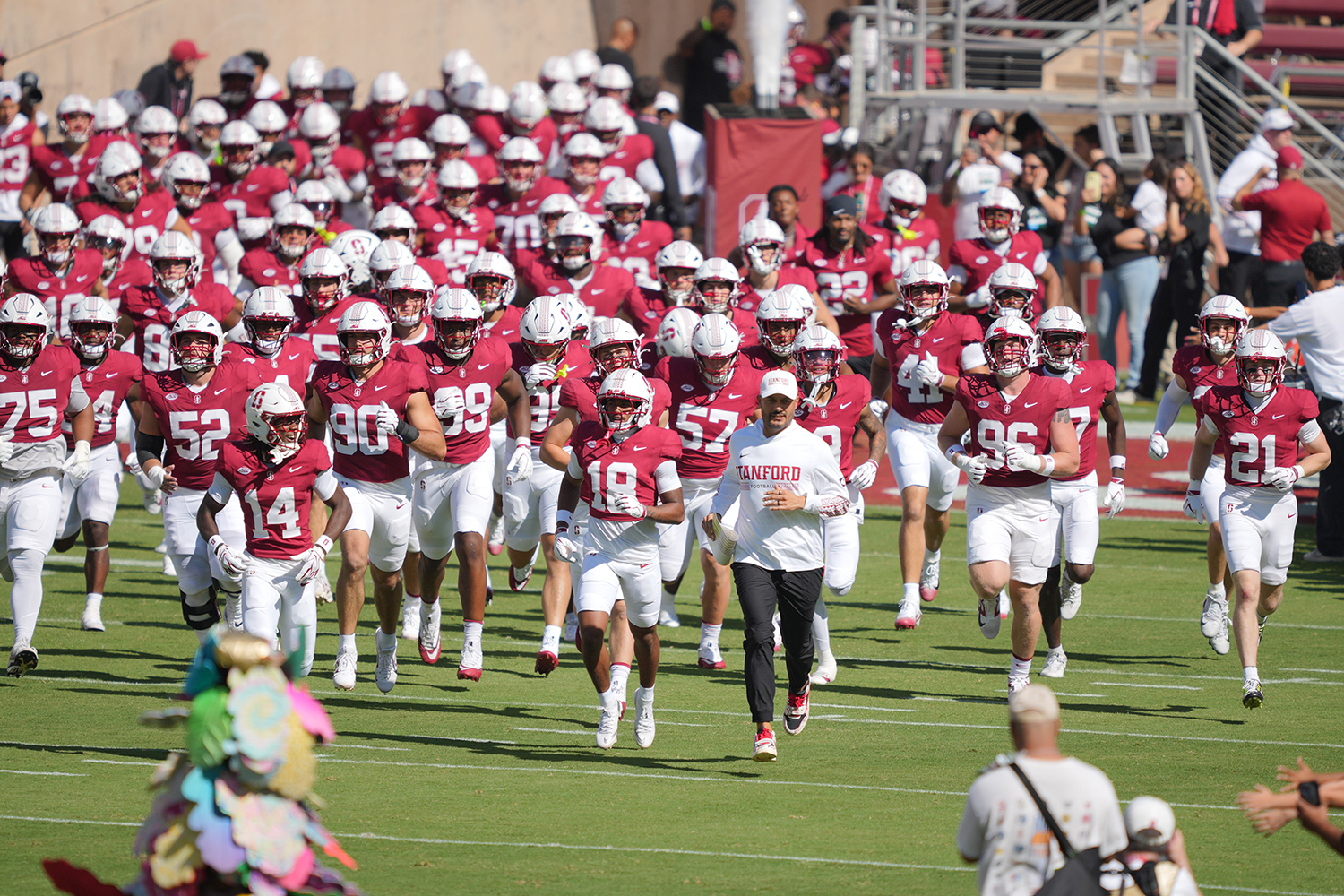 The Cardinal football team runs onto the field together at the start of a game.