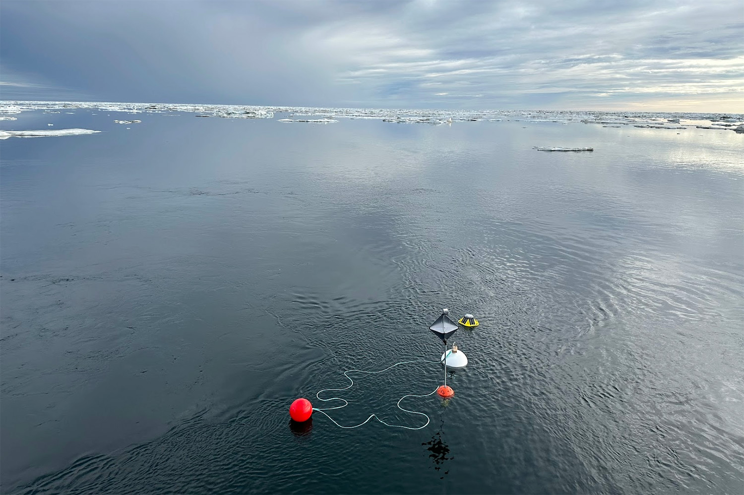 Scientific buoys float on calm Arctic waters, used to collect environmental data.