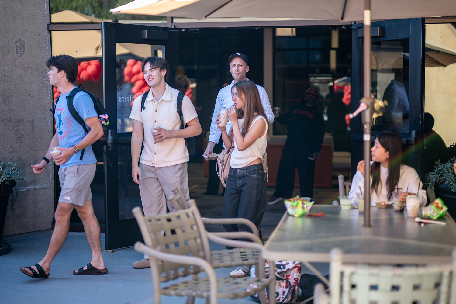 Students hold drinks and chat outside a campus café.