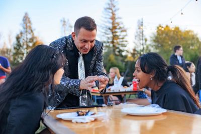 Magician performs for two students seated at a table.