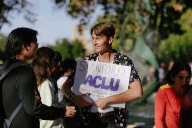 Student carrying an ACLU sign shaking hands with another student