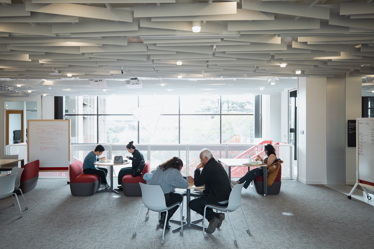 A seating area near the stairs with small tables and whiteboard for meeting and collaborating.