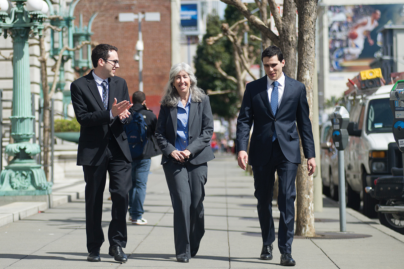Image of ELC students Evan Stein and Jason George walking down a street and conversing with Professor Deborah Sivas.