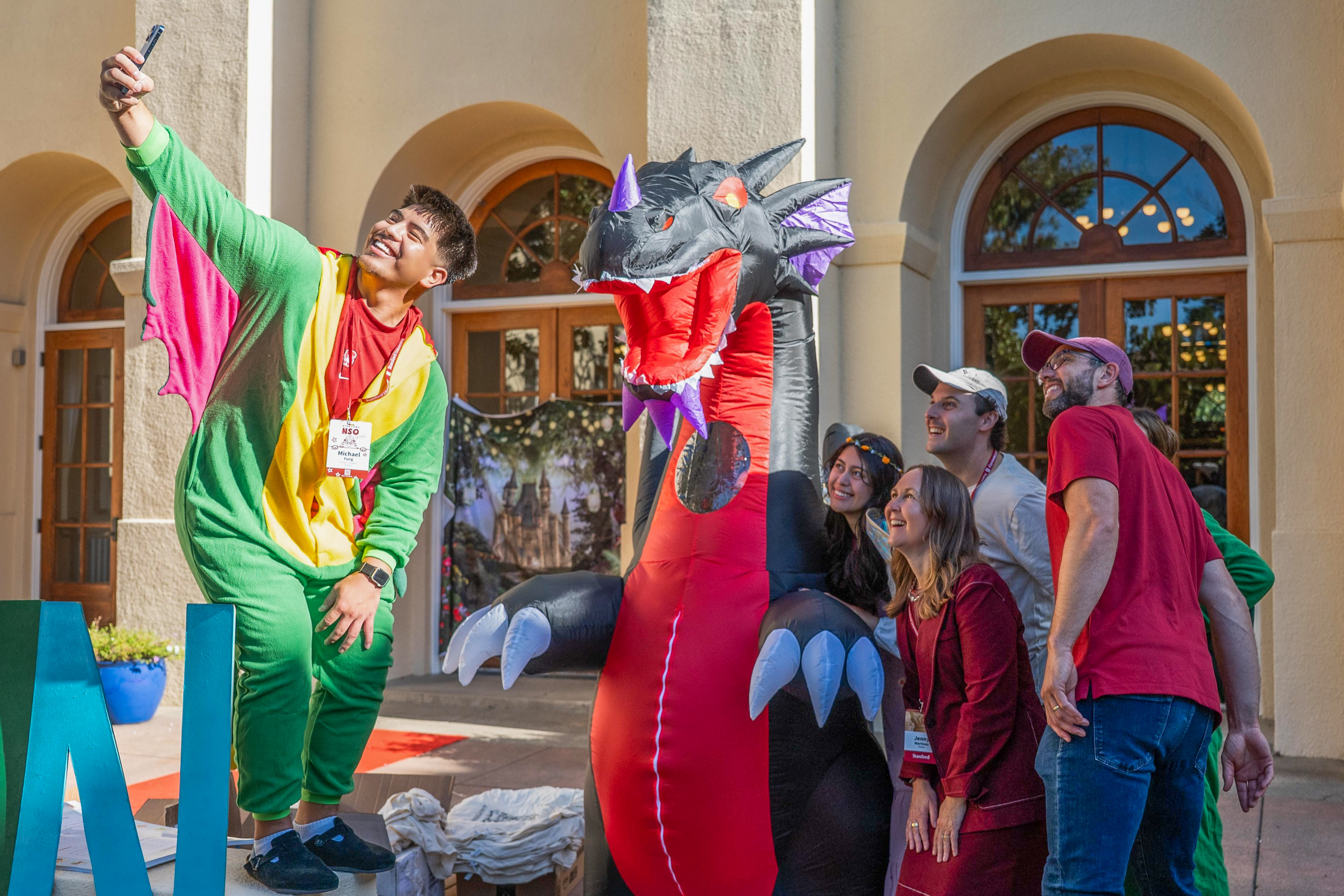 Provost Jenny Martinez and Stanford Football General Manager Andrew Luck join students to pose with an inflatable dragon on Move-In Day.