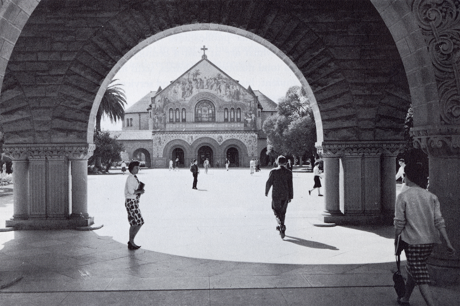 A view of Memorial Church and students walking on the Quad through the arcade. 