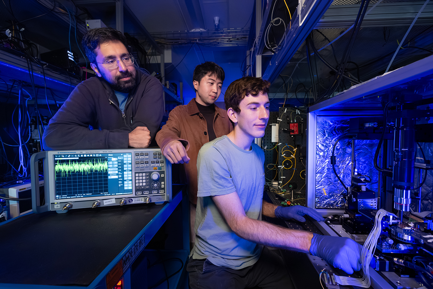 Stanford doctoral student Devin Dean prepares to measure an optical amplifier chip with Amir Safavi-Naeini and Taewon Park watching over his shoulder.