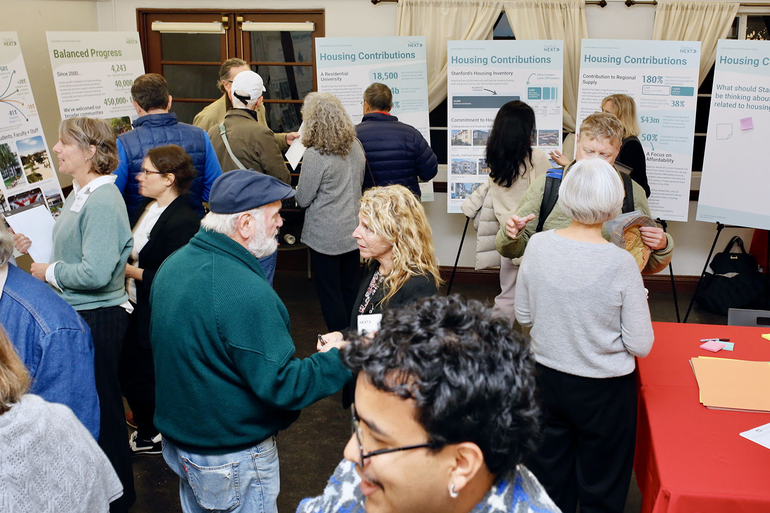 People roaming and reading information at a StanfordNext open house event in Palo Alto.