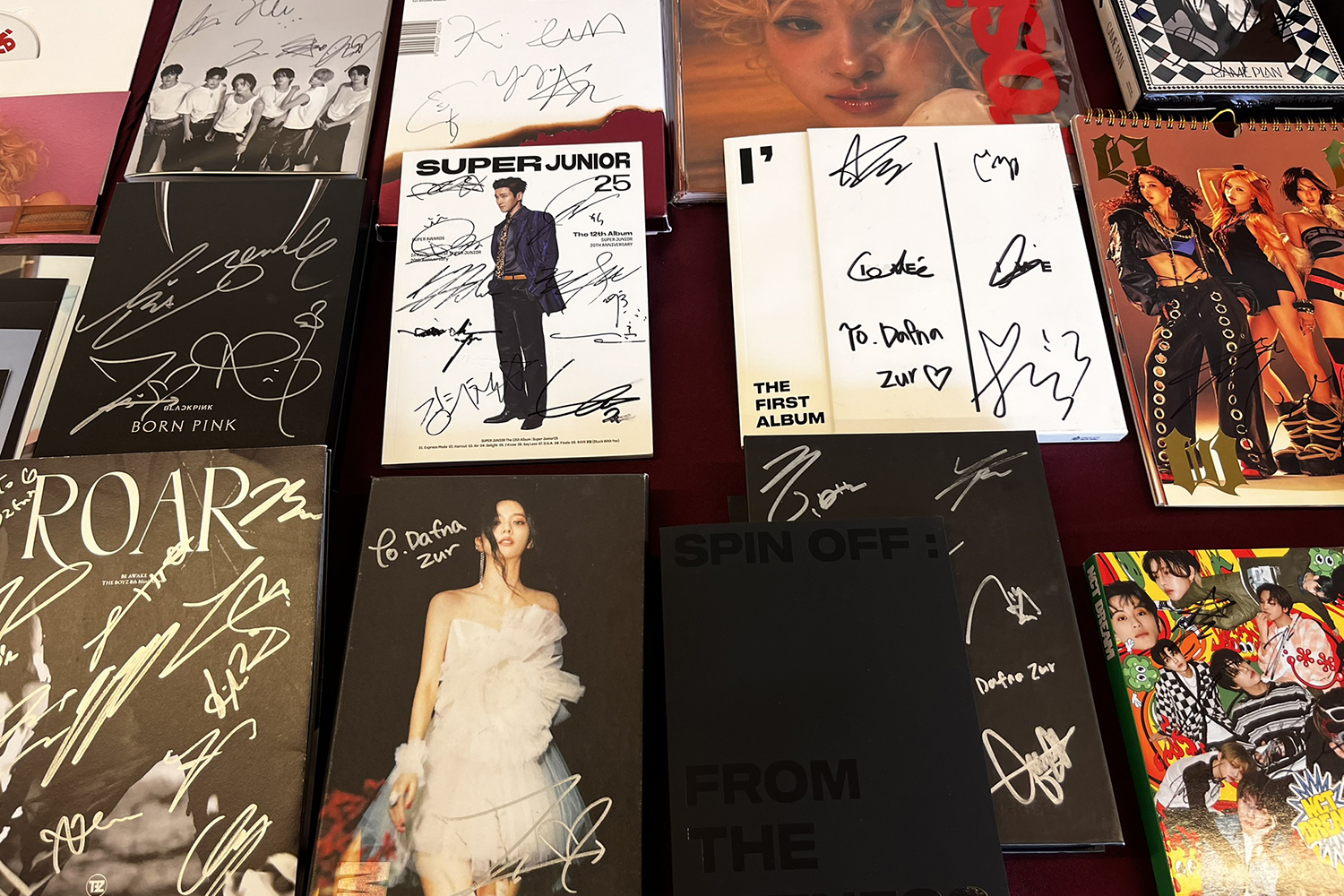 A collection of signed music albums and merchandise, featuring various artists' names and titles prominently displayed.