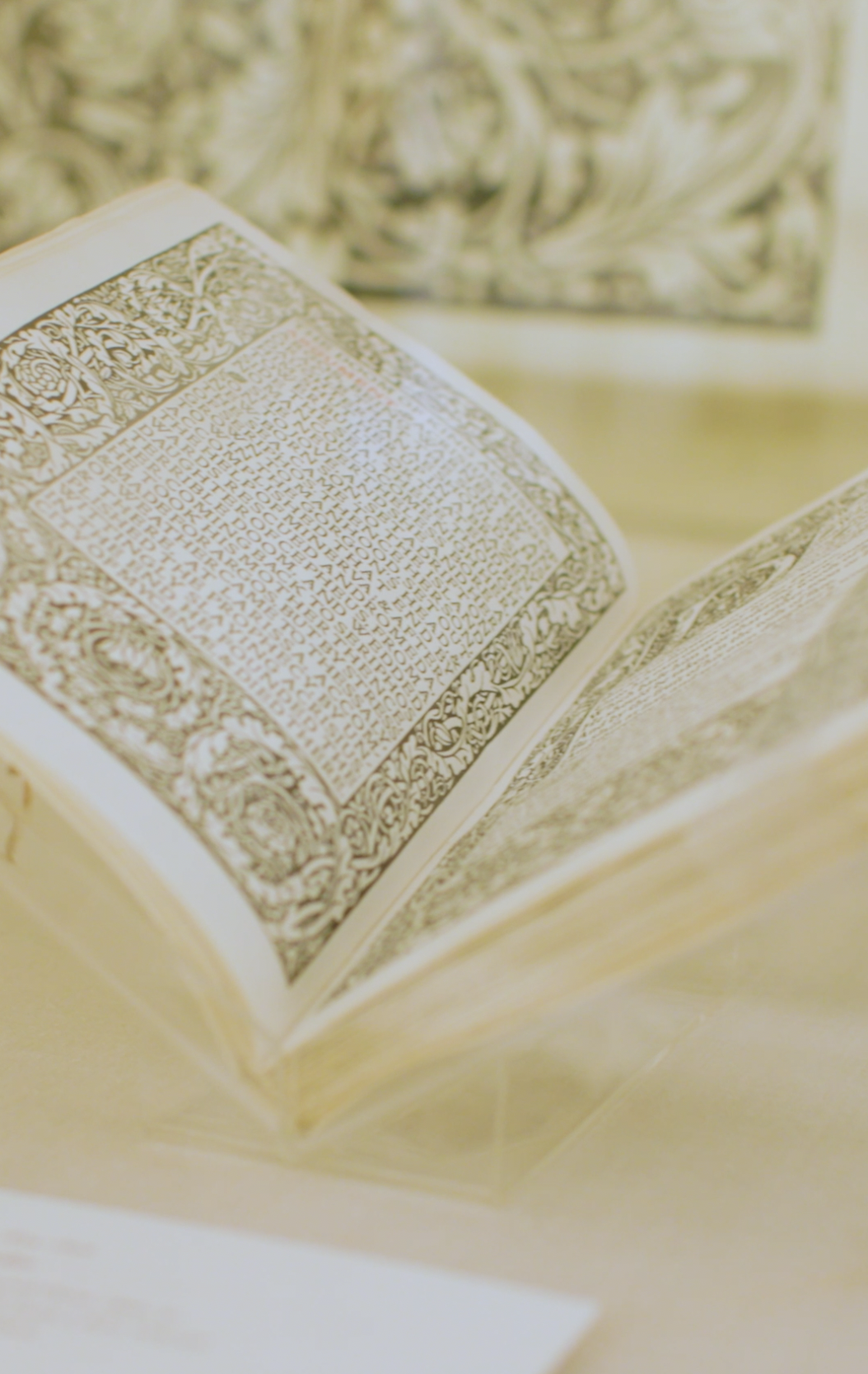 An open book displaying intricately designed pages with decorative borders and text, showcased in a museum display.