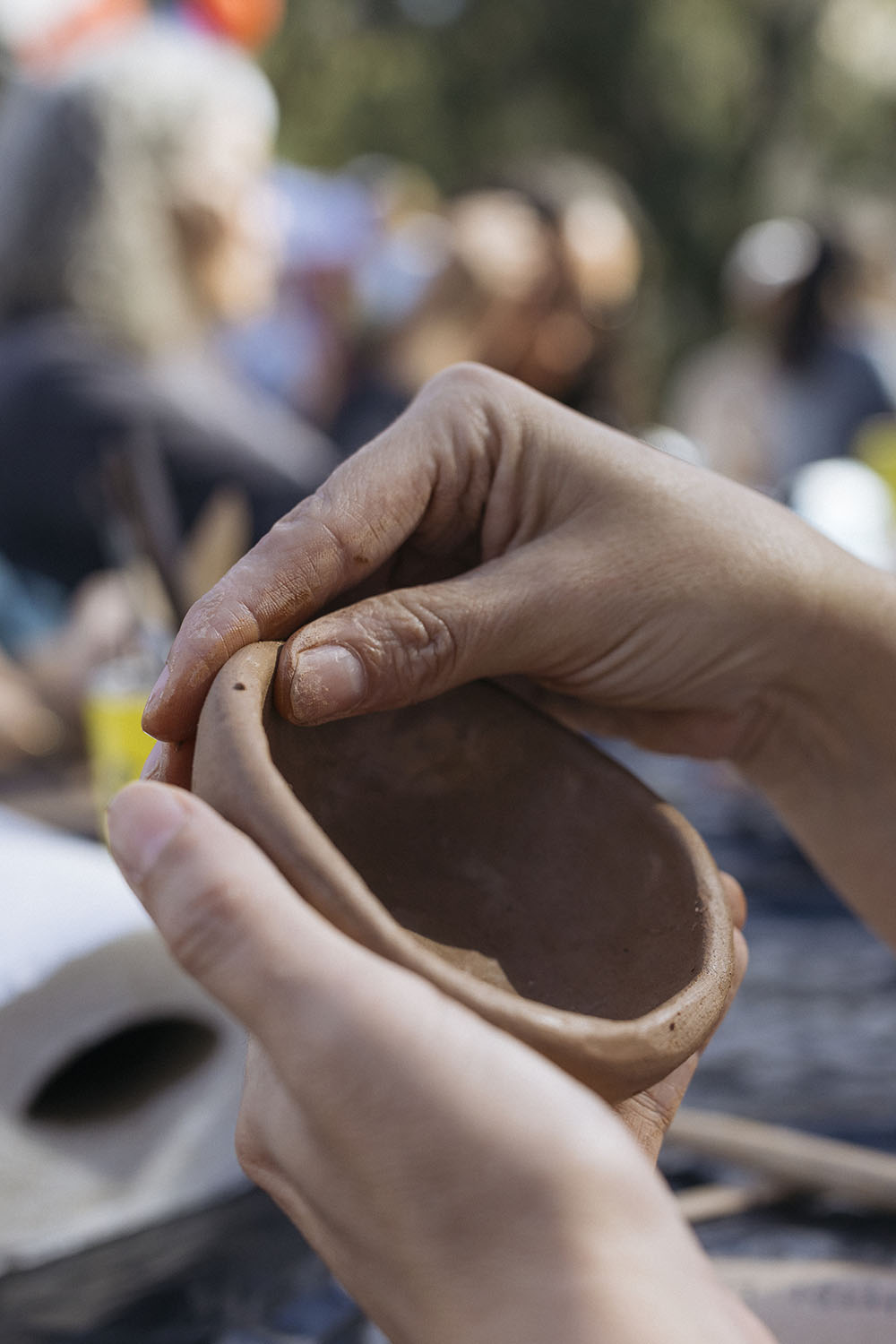 Hands shape a small clay bowl.