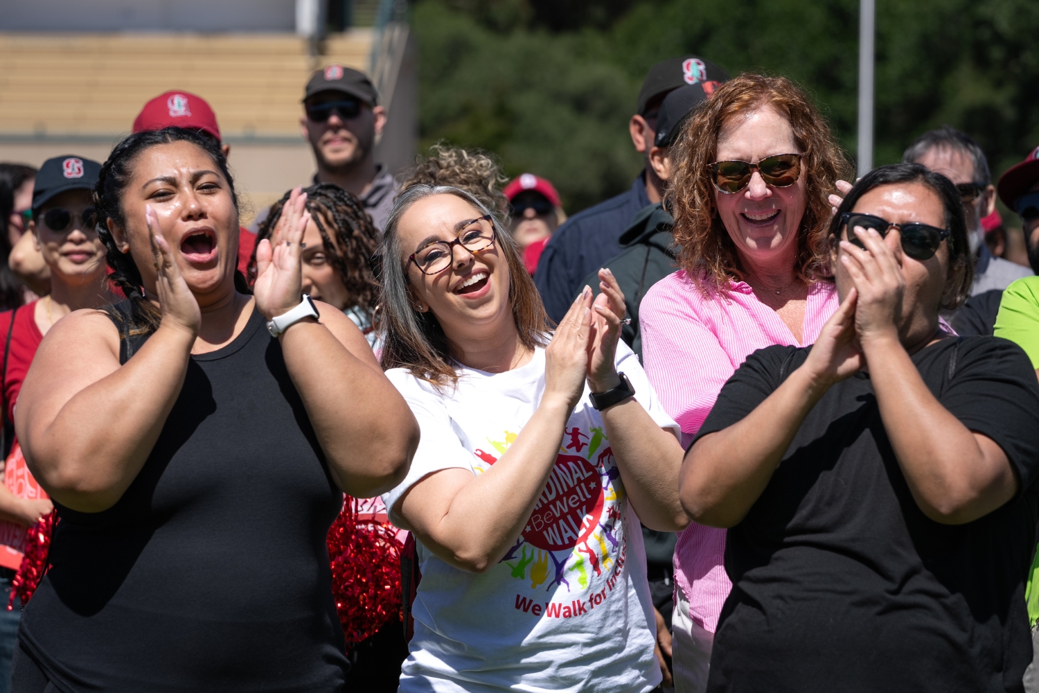 A group of people enthusiastically claps and cheers during a community wellness event, showcasing excitement and support.