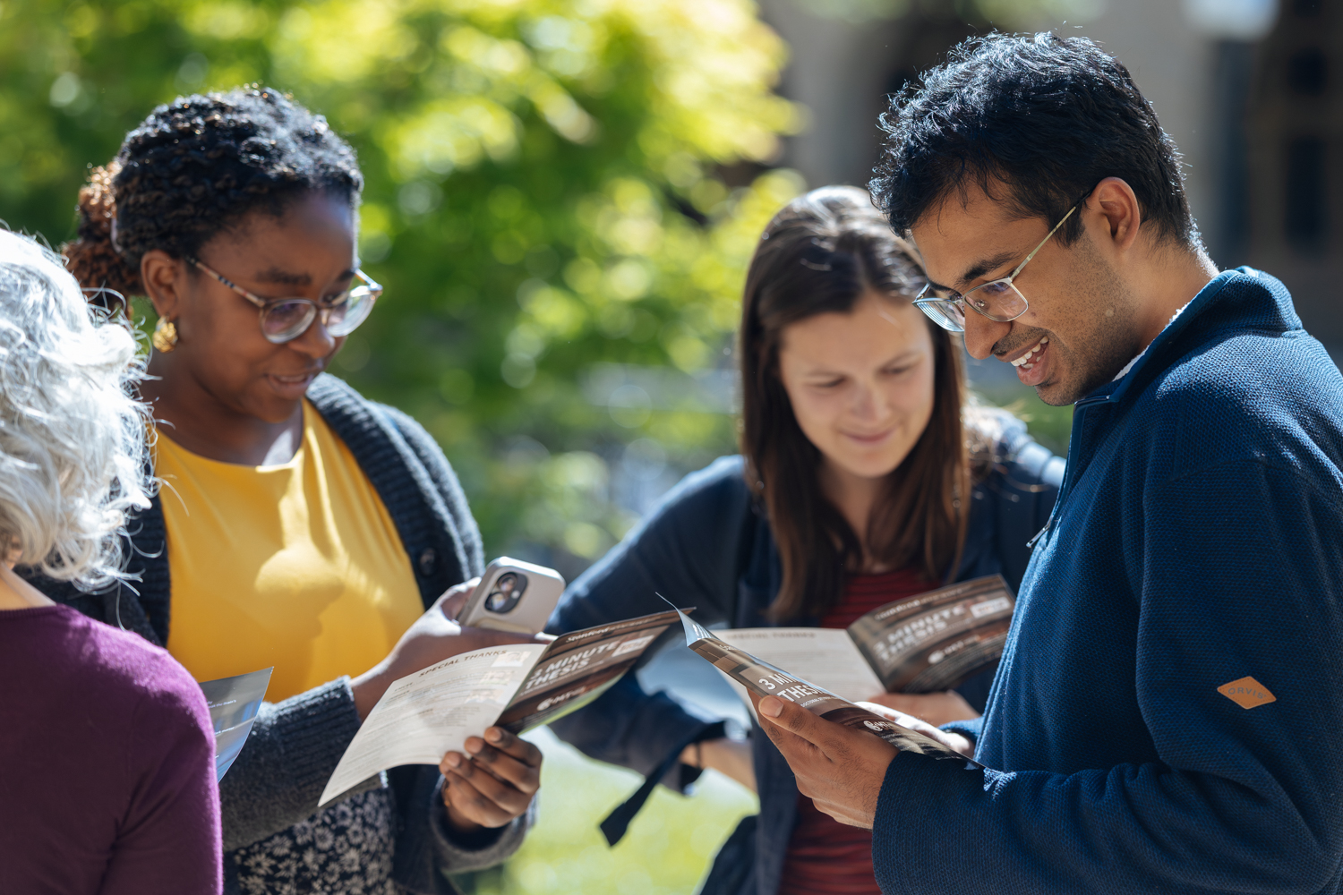 People gather outdoors to review programs together on a sunny day