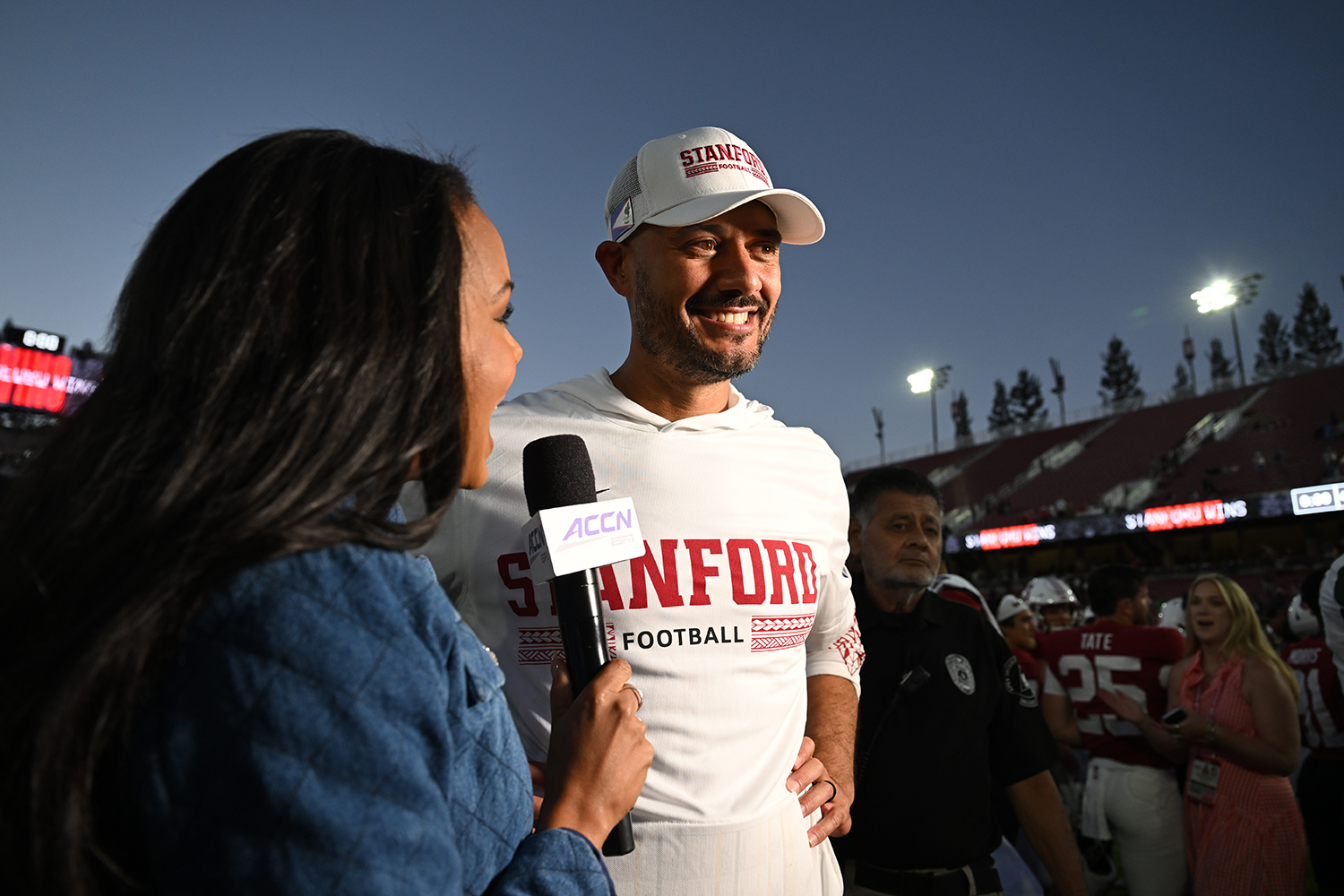 A reporter interviews head coach Tavita Pritchard on the field after a win.