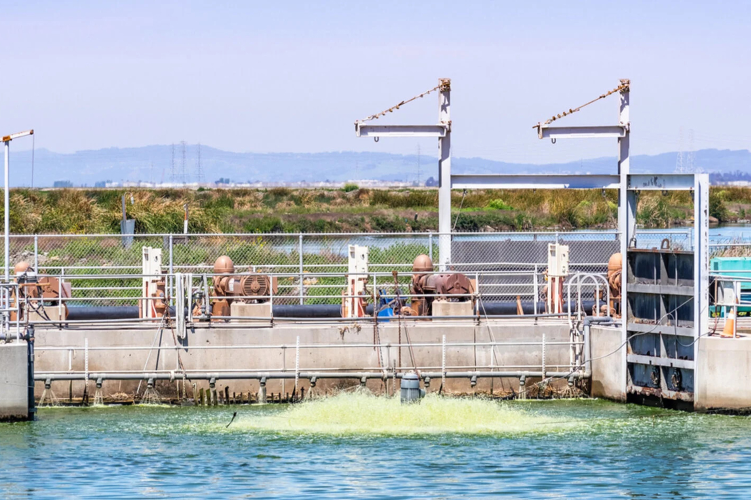 Pumps and pipes line a water treatment basin, where an aerator churns the water.
