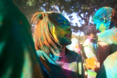 Student covered in colored dust, smiling.