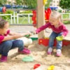kids squabbling over a toy in a playground sandbox
