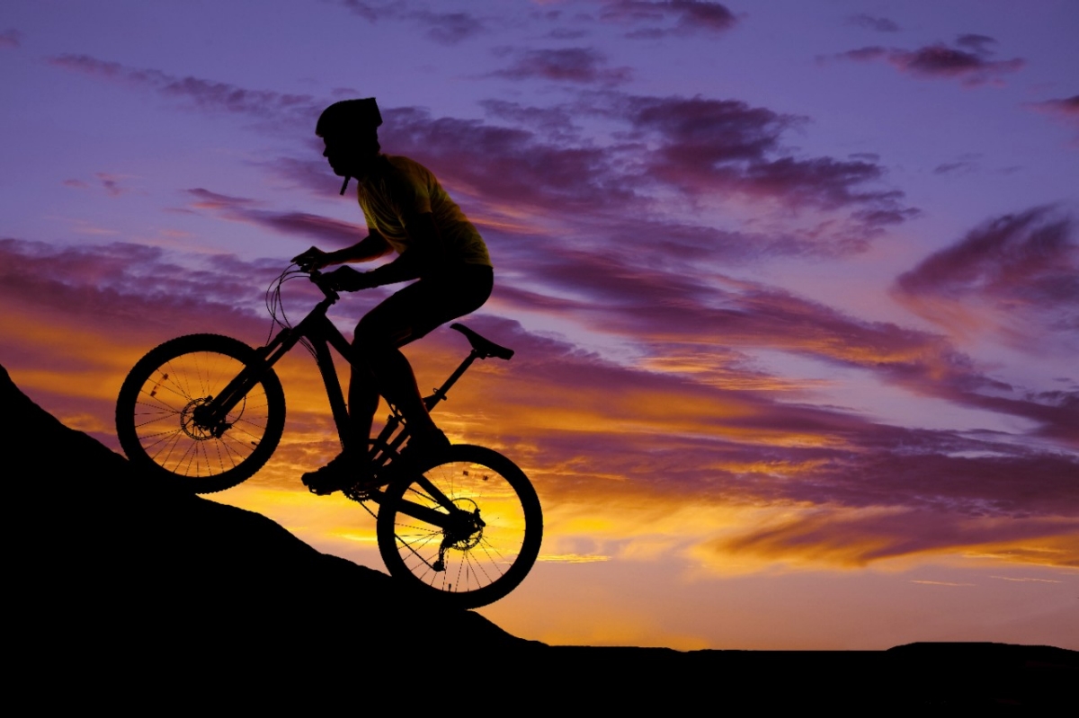A cyclist bikes up a mountain at sunrise.
