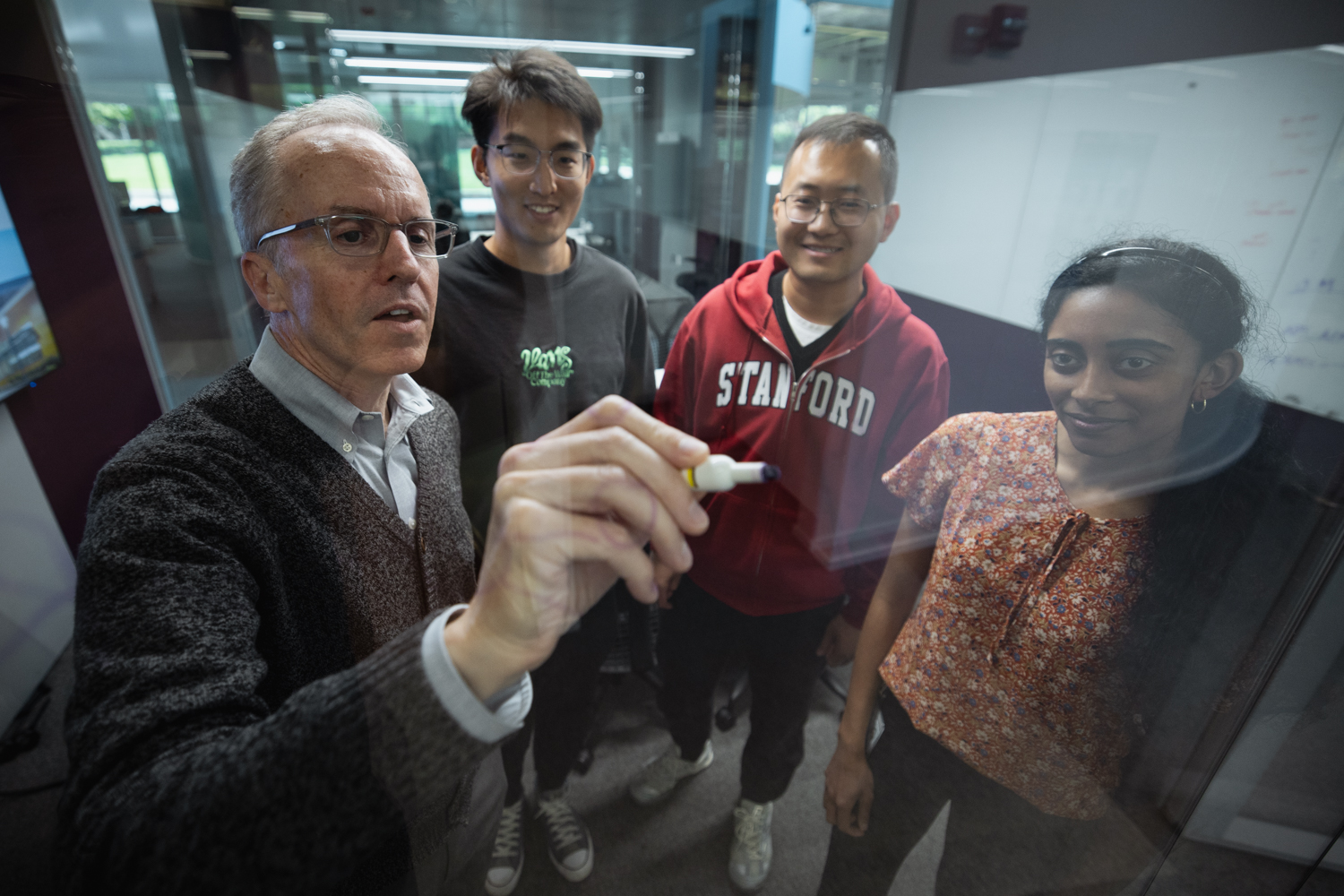 Image of Curtis Langlotz gesturing to a presentation on a TV screen while students sit and listen together.