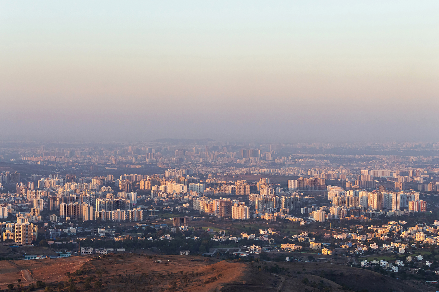 A panoramic view of Pune, India, at dusk, featuring various high-rise buildings and residential areas.